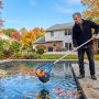 New York homeowner removing leaves from backyard swimming pool.